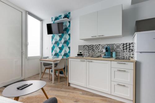 a kitchen with white cabinets and a table at Le Rêve Bleu in Brest