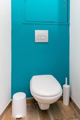 La salle de bains est pourvue de toilettes blanches et d'un mur bleu. dans l'établissement Le Rêve Bleu, à Brest