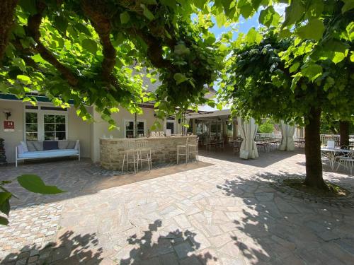 a patio with a table and chairs under a tree at Logis Hôtels - Hôtel Restaurant Domaine Les Falaises in Martel
