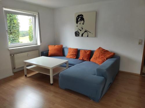 Apartment im Grünen, nähe A7, Legoland, 2 Schlafzimmer في فورينغن: غرفة معيشة مع أريكة زرقاء وطاولة