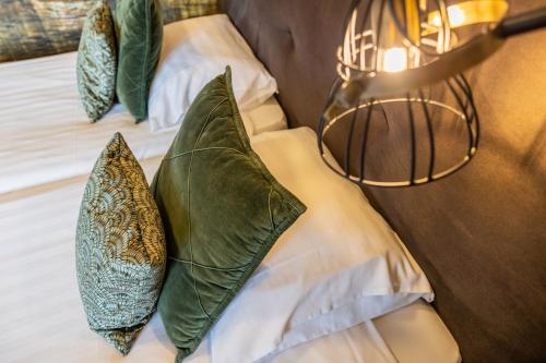 two green pillows on a bed with a lamp at Hotel De Walvisvaarder in Lies