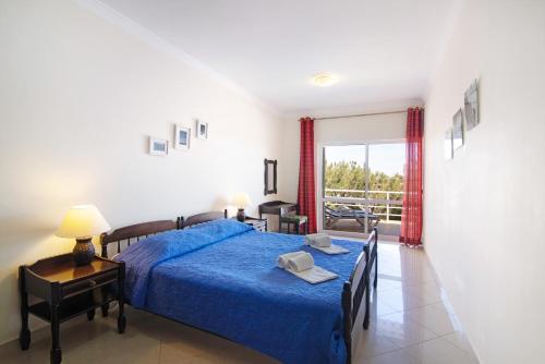 een slaapkamer met een bed met een blauwe sprei bij Yara Beach Apartments T1 in Albufeira