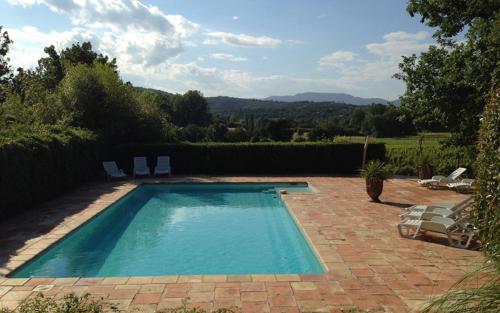 a swimming pool in a yard with chairs at Les Gites du Merle in Cogolin