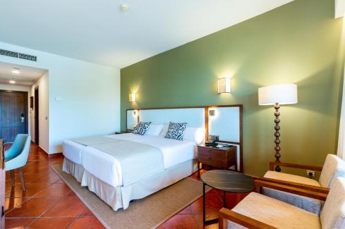 a bedroom with a white bed and a green wall at Puerto Antilla Grand Hotel in Islantilla