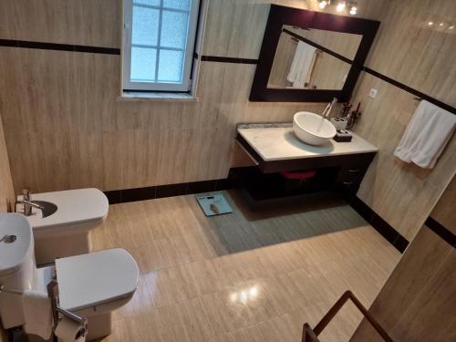 uma casa de banho com um lavatório, um WC e um espelho. em Villa do Outeiro em Figueira e Barros