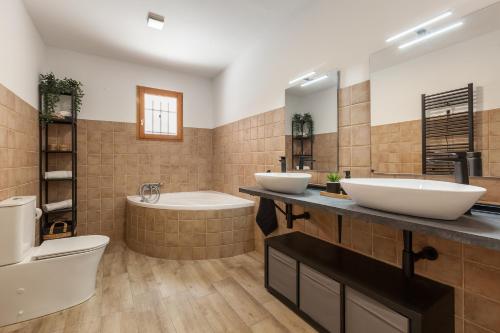 a bathroom with two sinks and a tub and a toilet at Les Roques in Castellnou de Bages