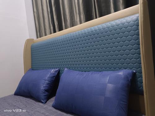 ein Bett mit zwei blauen Kissen in einem Schlafzimmer in der Unterkunft Bella Homestay Perlis in Arau