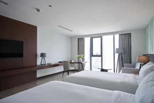 a hotel room with two beds and a flat screen tv at Signature by M Village Lê Thánh Tôn in Ho Chi Minh City