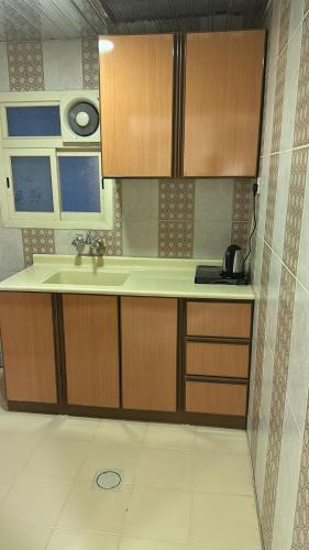 eine Küche mit Holzschränken und einem Waschbecken in der Unterkunft ريف الحسا للشقق الفندقيه in Al Hofuf