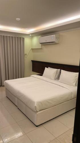 1 dormitorio con 1 cama grande con sábanas blancas en ريف الحسا للشقق الفندقيه, en Al Hofuf