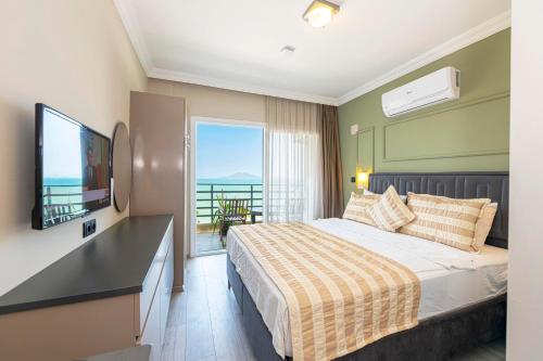 a bedroom with a bed and a television and a balcony at IDEE SUİTES Fethiye in Fethiye