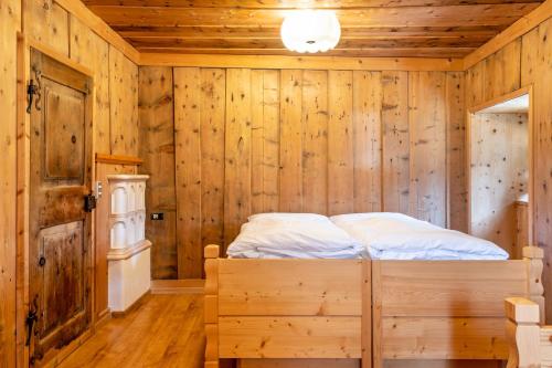 a bedroom with a bed in a wooden wall at Muncion Apparte in Pozza di Fassa