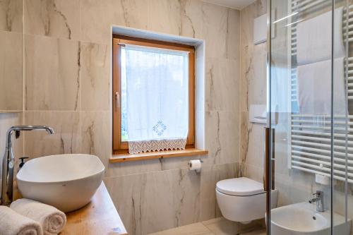 a bathroom with a sink and a toilet and a window at Muncion Apparte in Pozza di Fassa