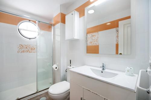 a bathroom with a sink and a toilet and a mirror at Apartamento primera línea in Chiclana de la Frontera