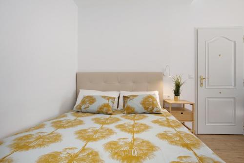 een slaapkamer met een bed met een gele en witte deken bij Estudio Erbania in Gran Tarajal