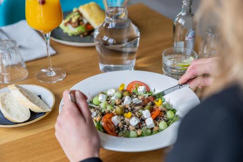 a woman sitting at a table with a bowl of salad at Hotel De Walvisvaarder in Lies