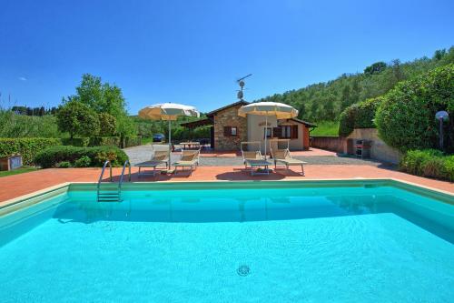 a swimming pool with chairs and a house at Cuccardino by PosarelliVillas in Bibbona