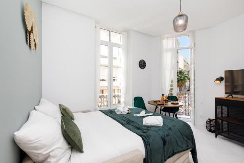 une chambre blanche avec un lit et une table dans l'établissement The Green Sun YourHostHelper, à Cannes