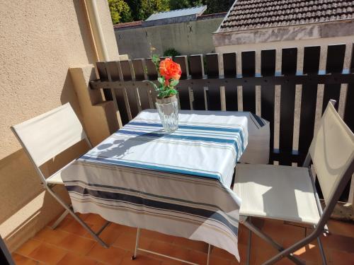 une table avec un vase et une fleur sur un balcon dans l'établissement APPARTEMENT DE 24 M2 à BARBOTAN-Minimum 21 nuits-CLIMATISé #VACANCES#CURE--lac et piscine à 1 km, à Cazaubon