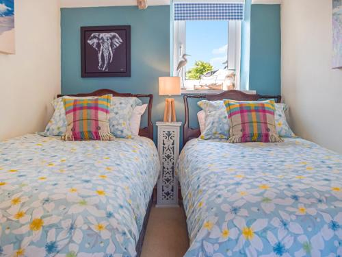 two beds in a bedroom with blue walls at Puffin Cottage in Abereiddy