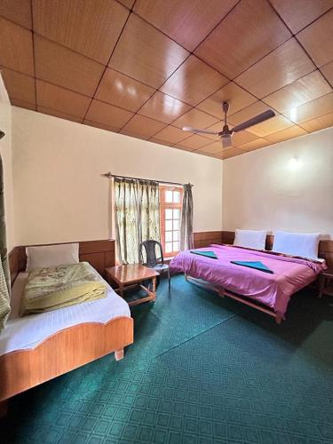 a bedroom with two beds and a table and a window at Zambala guest house in Deskit