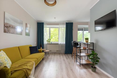 ein Wohnzimmer mit einem gelben Sofa und einem Tisch in der Unterkunft Kalevi City Center Apartment in Tartu