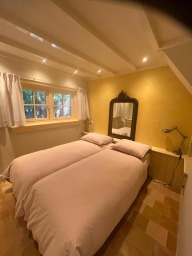 ein Schlafzimmer mit einem großen Bett und einem Spiegel in der Unterkunft Cottage Het Beukenootje in Aerdenhout