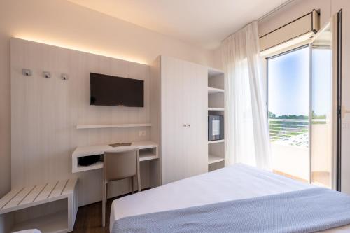 a bedroom with a bed and a desk and a television at Hotel Corfù in Pineto