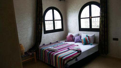 a bedroom with a bed with two windows at Villa shahinaz in Essaouira city in Essaouira