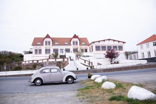 un pequeño coche blanco estacionado frente a una casa en The Falcon Hotel en Allinge