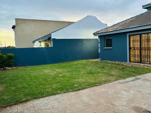 a house with a blue wall and a yard at Serenity Guest House in Soweto