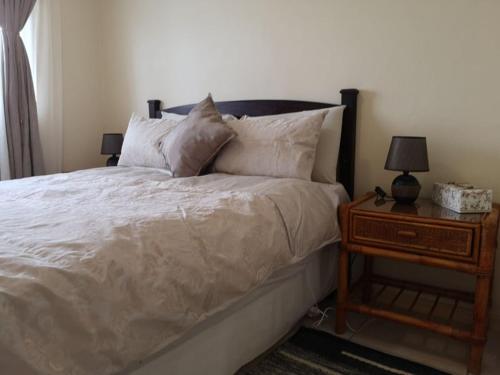 1 dormitorio con 1 cama y mesita de noche con lámpara en Kassiesbaai Cottage, en Arniston