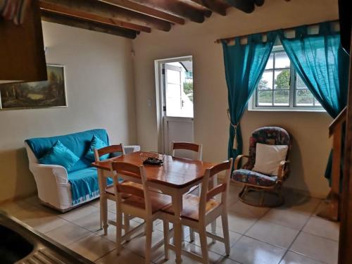 uma sala de jantar com uma mesa de madeira e cadeiras em Kassiesbaai Cottage em Arniston