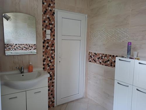 uma casa de banho branca com um lavatório e um espelho em Apartment Lia em Masline