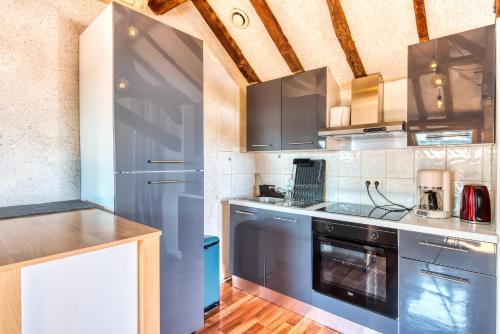 uma cozinha com armários azuis e um forno com placa de fogão em Sous les toits vue LOIRE em Bouchemaine