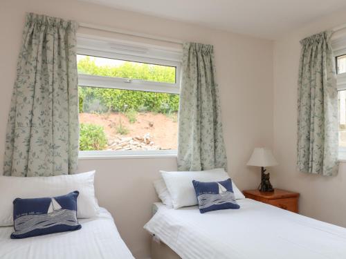 a bedroom with two beds and a window with curtains at Spindell in Kingsbridge