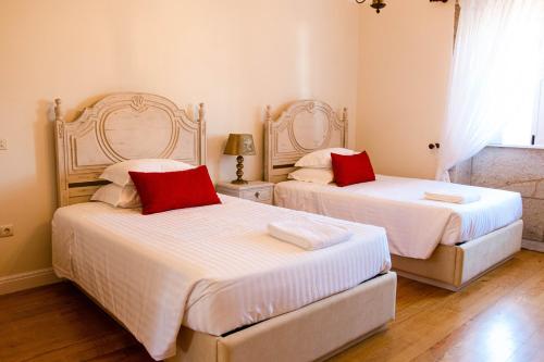 2 letti con cuscini rossi in una camera da letto di Quinta do Convento de Val´ Pereiras a Ponte de Lima