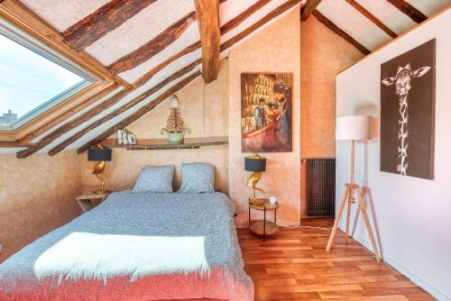 a bedroom with a bed and a ceiling with beams at Sous les toits vue LOIRE in Bouchemaine