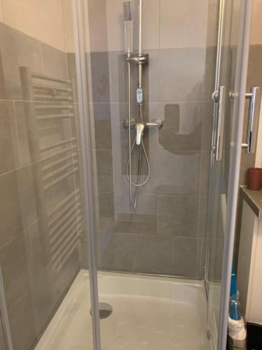 La salle de bains est pourvue d'une douche avec une porte en verre. dans l'établissement Le Val Fleuri, à La Bourboule
