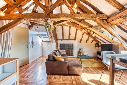 a living room with wooden ceilings and a leather couch at Sous les toits vue LOIRE in Bouchemaine