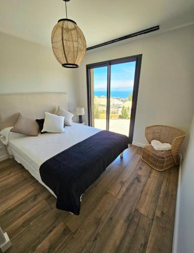 une chambre avec un grand lit et une grande fenêtre dans l'établissement Appartement prestige avc piscine - Village Furiani, à Furiani