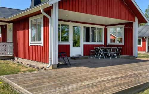 a red house with a table and chairs on a deck at Gorgeous Home In Vittaryd With Wifi in Kvänarp