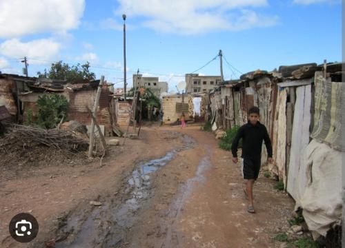 a young man walking down a dirt road in a village at Plage in Temara