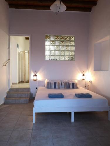 1 dormitorio con 1 cama blanca grande y 2 almohadas en Asimina's beach house, en Ándros