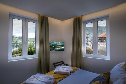 a bedroom with two windows and a bed in it at A Tendinha - Guest House in Peso da Régua