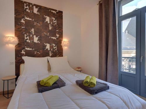 ein Schlafzimmer mit einem Bett mit zwei grünen Hausschuhen darauf in der Unterkunft La Bourboule Centre - Magnifique T3 avec Balcon, Wi-Fi, Animaux Acceptés - FR-1-608-119 in La Bourboule