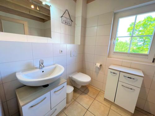 a white bathroom with a sink and a toilet at Strandpark Sierksdorf H054 in Sierksdorf