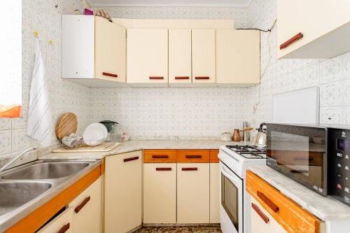 una pequeña cocina con armarios blancos y fregadero en Habitacion privada y tranquila, en Alicante