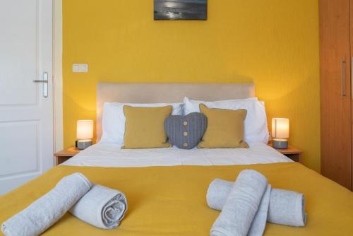 a bedroom with a bed with yellow walls and two lamps at 4 Meadow View in West Down