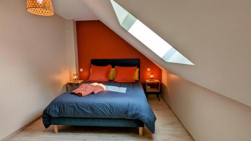聖瑪麗拉布朗什的住宿－Le Clos des écureuils，一间卧室配有一张带橙色墙壁和天窗的床。